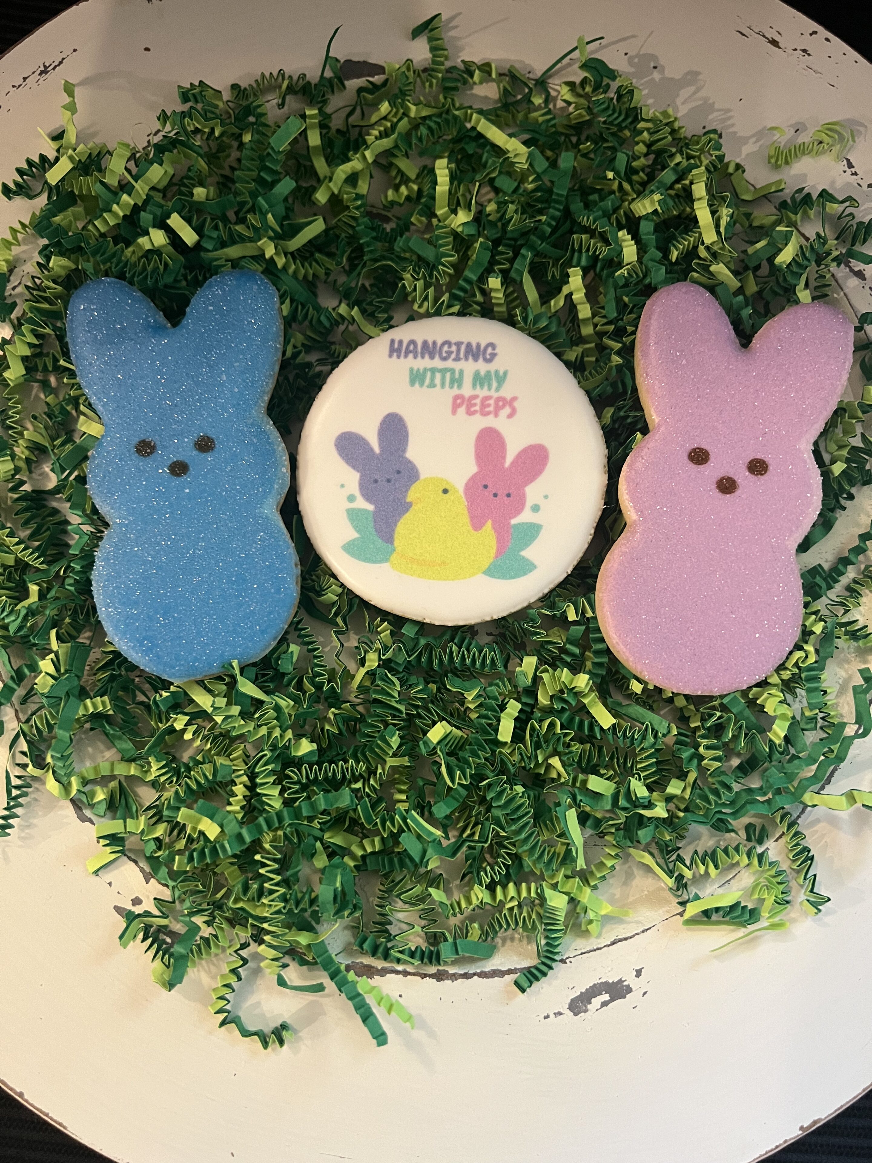 Easter-themed cookies on green shredded paper.